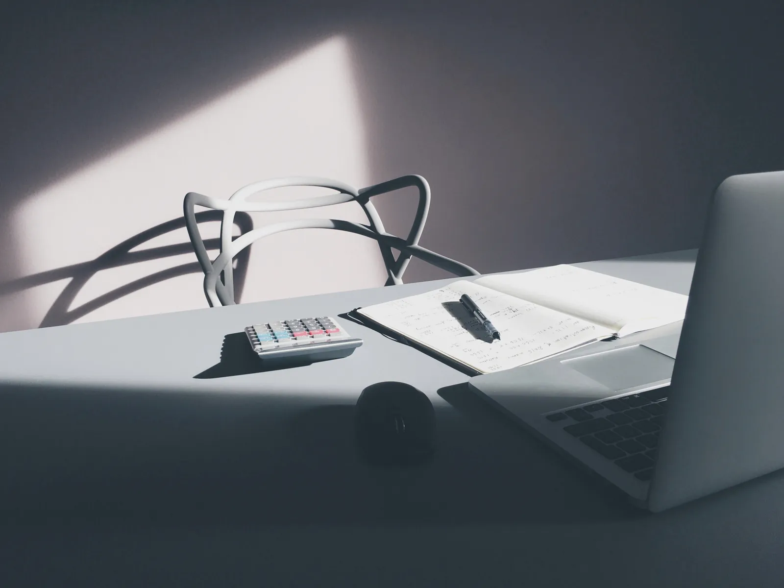 Escritorio de trabajo con calculadora, libreta de apuntes y computadora portátil